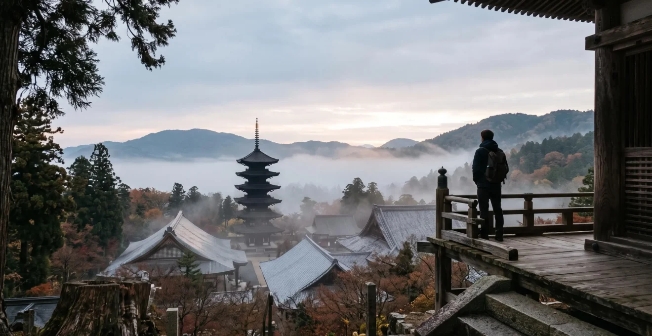 Voyageur contemplant en silence un vaste complexe de temples japonais classé au patrimoine mondial, silhouette de pagode se détachant dans la brume matinale